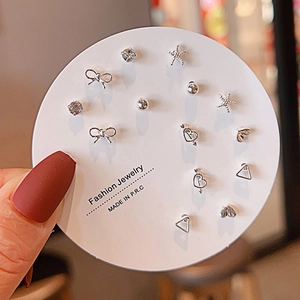 Close-up of a 7-piece silver stud earring set with stars and bows on round card