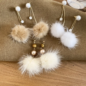 Detailansicht von Winter-Pompon-Ohrringen mit Perlen und Kristallen auf Strickstoff