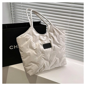 Close-up of white quilted puffer tote bag detail with fashion brand label and soft nylon texture