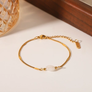 Detail of gold stainless steel chain bracelet featuring an oval white natural stone
