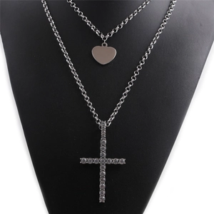 Detail of silver double layer necklace with heart pendant and rhinestone cross charm
