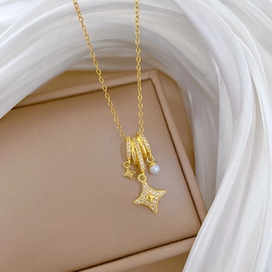 Detail of gold titanium necklace with pearl and sparkling star pendant on white silk
