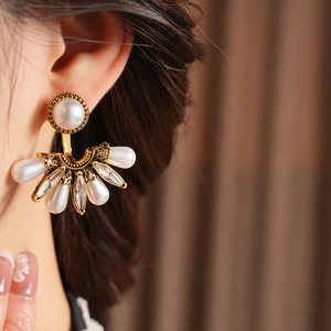 Detailed close-up of vintage fan-shaped pearl and diamond earrings worn by a model