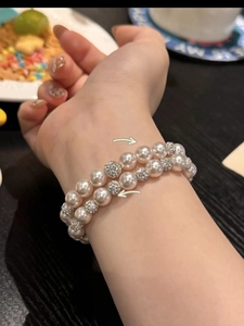 Close-up of double-layer pearl bracelet with diamond-encrusted spheres on woman's wrist