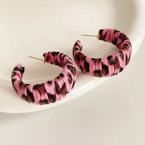 Detail of pink and black leopard print fabric wrapped hoop earrings on a white plate