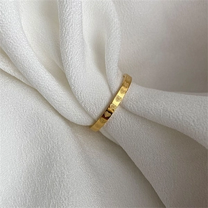 Minimalist 18k gold plated titanium heart engraved ring on soft white fabric background
