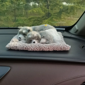 Detail of grey and white plush husky toys resting on a soft beige mat inside a car