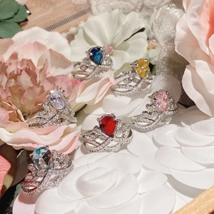 Macro detail of pear-cut gemstone rings in various colors on floral background