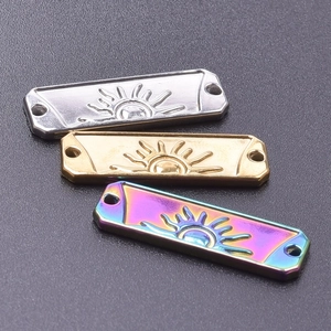 Macro view of sun-embossed rectangular steel charms in silver, gold, and rainbow finishes