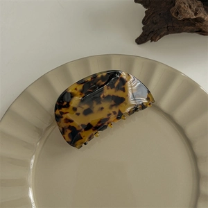 Detail view of large tortoise shell acetate hair claw clip on a decorative dish