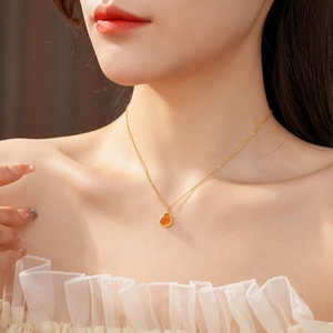 Detailed view of a gold-plated Buddha pendant necklace with amber teardrop gemstone