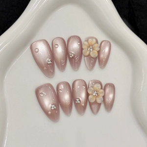 Handmade almond press-on nails with 3D floral relief and pearl finish on ceramic tray