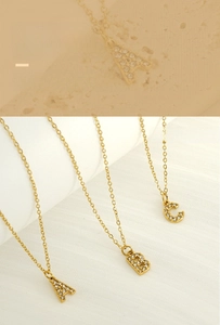 Macro detail of gold initial necklaces with pavé crystals and elegant link chains
