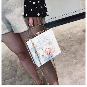 Detail of white floral box bag featuring 3D pink roses and pearl handle chain
