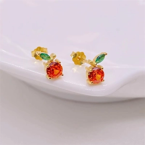 Macro view of S925 silver cherry stud earrings with red and green zircons