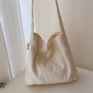 Macro detail of floral embroidery on a cream cotton tote bag with a simple wish label