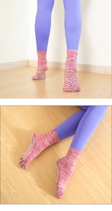 Detail view of pink yoga five-toe socks with non-slip white grip dots on soles
