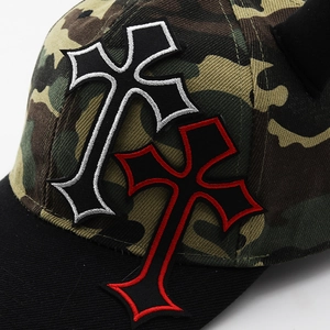 Detail shot of embroidered pink and black crosses on a camo fabric devil horn baseball cap