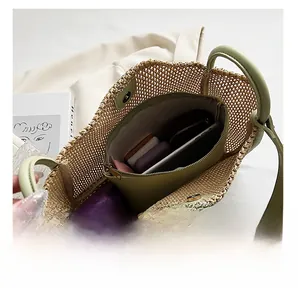 Detail view of large straw tote with green leather straps and spacious inner organizer