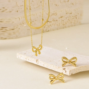 Détail d'un ensemble collier et boucles d'oreilles dorés avec pendentif nœud papillon