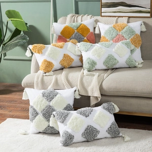 Close-up of tufted geometric cushion covers with handmade tassels in a cozy home setting
