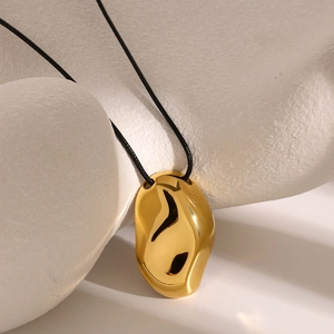 Dettaglio di un ciondolo a ciottolo organico in oro 18k lucido su cordino nero