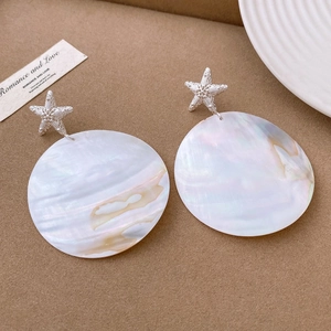 Detailed view of silver starfish studs with large round iridescent white shell pendants