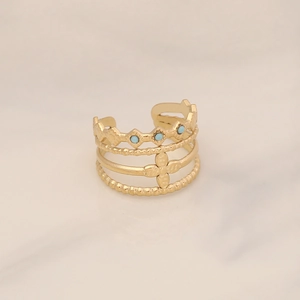 Detailed view of gold multi-layer open ring with turquoise bead and clover motif on marble