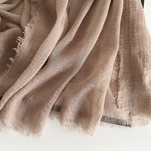 Close-up of light brown cotton linen scarf showing breathable fabric and raw fringe edges