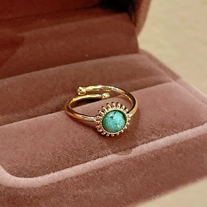 Macro shot of gold-plated vintage ring featuring green stone in luxury velvet gift box