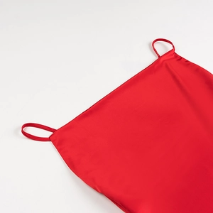 Dettaglio dello scollo dell'abito in raso rosso con spalline sottili e finitura lucida