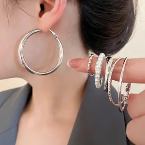 Elegantes silbernes Ohrring-Set mit geometrischen Creolen und Perlen auf der Hand