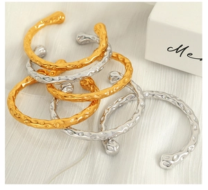 Close-up of gold and silver hammered stainless steel open bracelets on white background