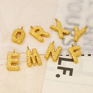 Golden embossed letter pendants with unique textures on a textured beige background