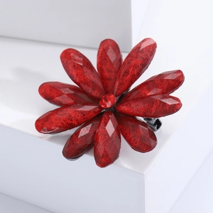 Macro view of red faceted resin flower brooch with a central sparkling rhinestone