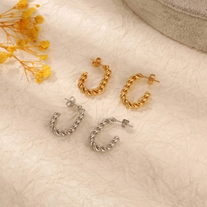 Classic twisted C-shape hoop earrings in gold and silver finish on textured paper
