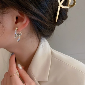 Close-up of silver earrings with rhinestones and matching ring on a stylish model