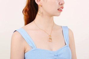 Close-up of a woman wearing a gold interlocking double ring necklace and earrings set