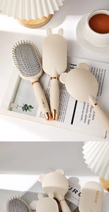 Detail of cute cream massage hairbrush with bunny ears and golden electroplated base