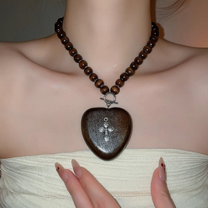 Détail macro du collier gothique en perles de bois avec pendentif cœur et croix
