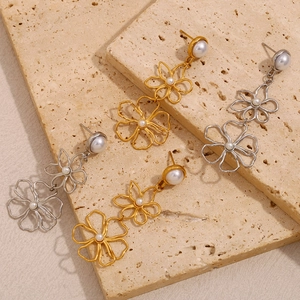 Detail of 18K gold and silver plated flower stud earrings with pearls on stone background