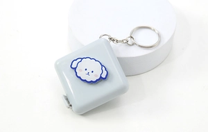 Close-up of a blue mini tape measure with sheep cartoon and metal keychain attachment