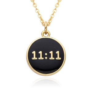 Macro view of a 18K gold plated necklace with a black enamel 11:11 circular pendant