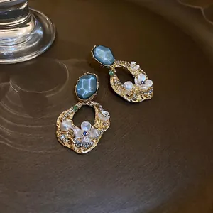 Boucles d'oreilles vintage avec pierre bleue et design floral doré sur plateau