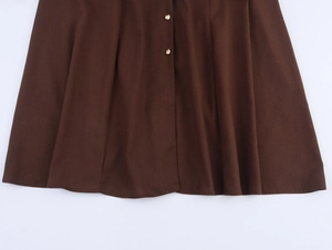 Detail view of dark brown linen-cotton dress with pleats and gold metal buttons