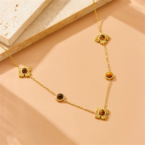 Gold flower necklace set with brown tiger eye stones on minimalist stone background
