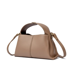 Macro detail of brown leather texture and metal snap button on a square handbag