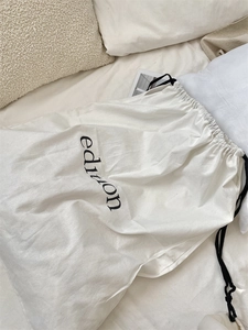 Detail of a minimalist white cotton drawstring bag featuring the black edition text print