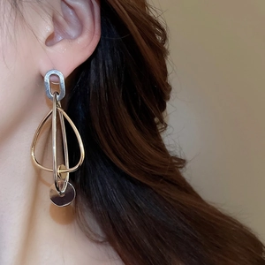Gros plan d'élégantes boucles d'oreilles géométriques bicolores en métal poli or et argent