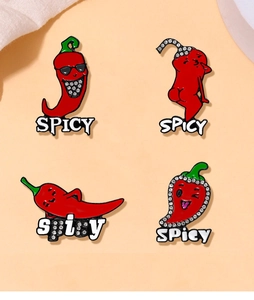 Set of four red chili enamel pins with spicy text and rhinestones on beige fabric